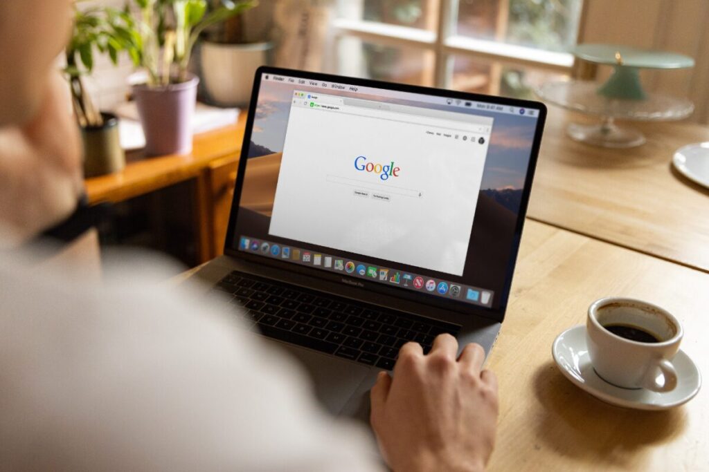 カフェでコーヒーを飲みながらノートパソコンでGoogle検索する手元