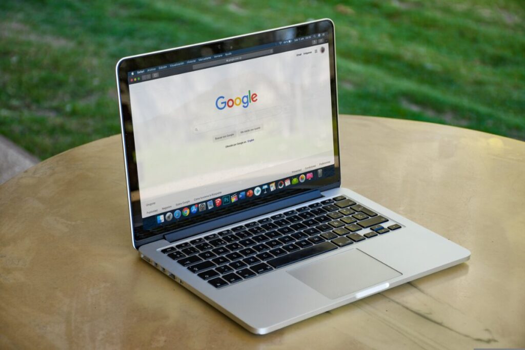 屋外テーブルでノートパソコンにGoogle検索画面を表示する様子