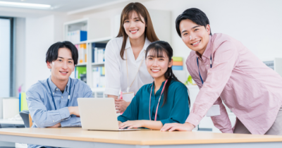 オフィスでノートパソコンを囲んで打ち合わせをする若いビジネスチーム